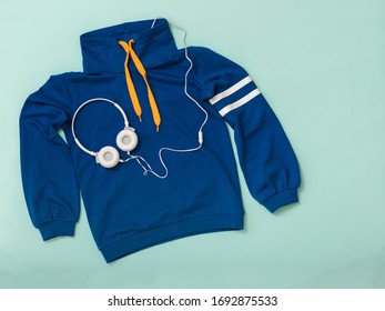 Dark blue hoodie and white headphones on a blue background. Sports lifestyle accessories. - Powered by Shutterstock