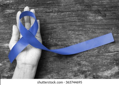 Dark blue ribbon symbolic for colon - colorectal cancer, Juvenile Arthritis and Acute Respiratory Distress, Guillain Barre Syndrome (ARDS), awareness on supporter's hand (isolated with clipping path)