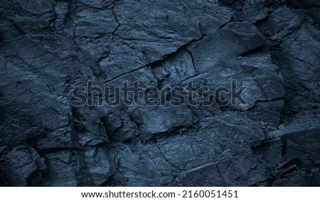   Dark blue rock texture. Toned rough mountain surface with cracks. Close-up. Stone background with space for design. Wallpaper.                              