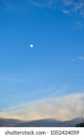 Dark blue sky background with clouds and moon in the daytime.