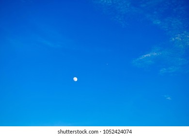 Dark blue sky background with clouds and moon in the daytime.