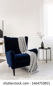 Dark Blue Velvet Wing Back Chair With Grey Blanket In Trendy Living Room