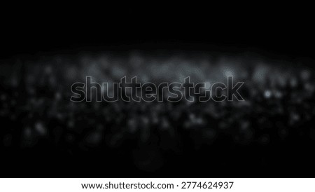 A dark, blurred image of a large crowd of people, possibly at a concert or event, with lights in the background. The image is out of focus, creating an abstract effect.