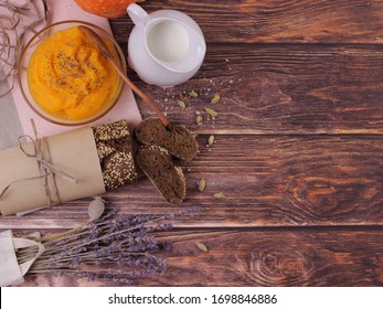 Dark Bread On A Rustic Wooden Board. Bread In The Bakery Has Just Come From The Oven. Fresh Baking On A Wooden Table. Breakfast. Bred, Milk And Pumpkin Porridge.