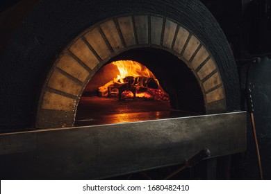 Dark Brick Pizza Oven With Fire In Restaurant 