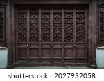 The dark brown ancient wooden door panel built in traditional Chinese architectural style and pattern at the main entrance to an old house in China