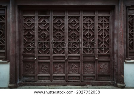 The dark brown ancient wooden door panel built in traditional Chinese architectural style and pattern at the main entrance to an old house in China