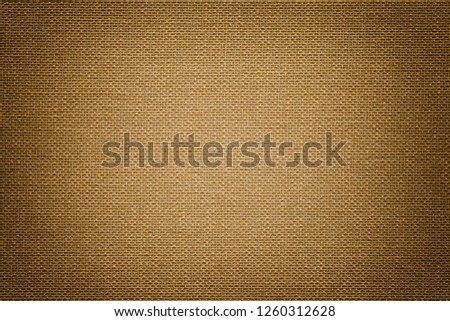 Dark brown background from a textile material with wicker pattern, closeup. Structure of the bronze fabric with texture. Cloth backdrop with vignette.