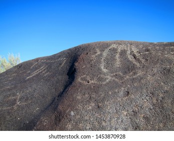 Dark Brown Boulder With Historical Archaeological Petroglyph Rock Carvings At Celebration Park In Idaho.