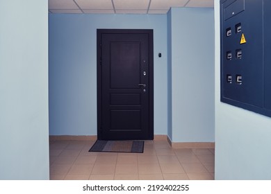 Dark Brown Door In The Entrance Of An Apartment Building With Blue Corridor Walls