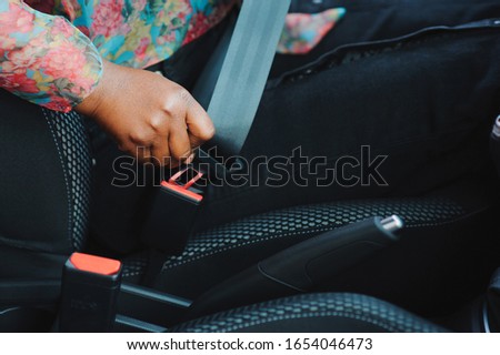 Dark brown skin African woman hand buckling safety belt in the car for automobile accident safety concept 商業照片 © 