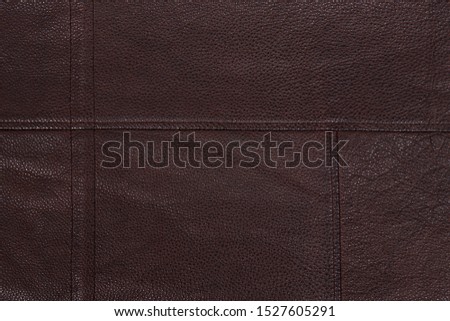 Dark brown stitched leather background. Asymmetric seams. Rough surface with free space. Expensive material sample. Handwork. Seat upholstery or leather jacket.