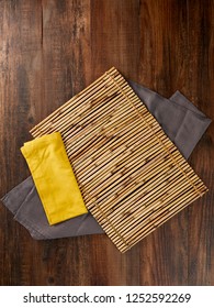 Dark Brown Wood Table Texture With Bamboo  Mat And Two Fabric Napkins Top View Background