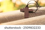 Dark brown wooden cross on an old open book, symbolizing the spread of Jesus Christ’s love among Christians, reflecting faith, devotion, and the importance of Christian teachings.