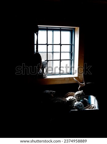 Dark cabin, interior and light by window in home with gear, tools or fishing equipment, rope or net for storage. Vintage cottage, shed and inside old rustic house, room or abandoned wood architecture