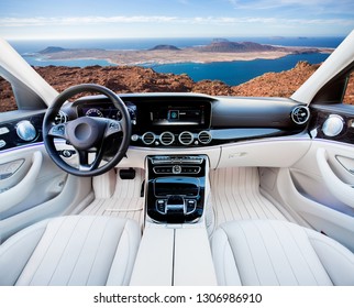 Dark Car Interior - Steering Wheel, Shift Lever And Dashboard. Car Modern Inside. Front View On Sunset And Sea Background. The Sun Shines In The Glass.glare