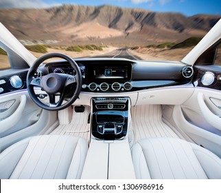 Dark Car Interior - Steering Wheel, Shift Lever And Dashboard. Car Modern Inside. Front View On Sunset And Sea Background. The Sun Shines In The Glass.glare