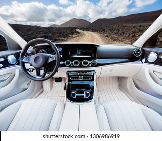 Dark Car Interior - Steering Wheel, Shift Lever And Dashboard. Car Modern Inside. Front View On Sunset And Sea Background. The Sun Shines In The Glass.glare