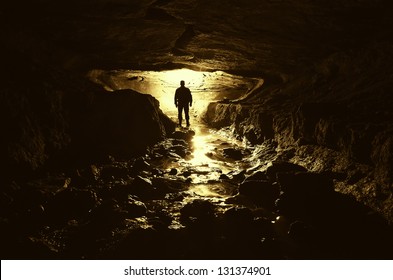 Dark Cave With Man Silhouette And Water