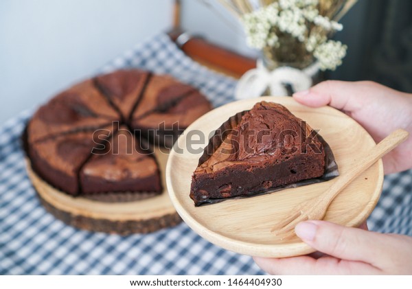 Dark Chocolate Brownie. Woman\
holding a wooden plate of brownies with chocolate chips\
filled.