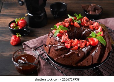 Dark Chocolate Bundt Cake with Ganache Icing and strawberry on dark stone or concrete table background. Festive cake. Selective focus