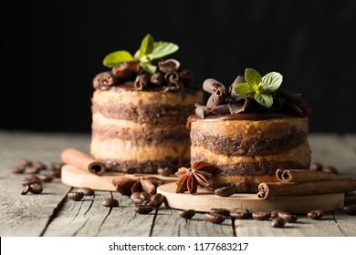 Dark chocolate cakes on black slattern board with mint, cinnamon, coffee beans on a wooden  background. Tasty dessert food concept.