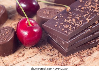 Dark Chocolate With Cherry On Wooden Table. Chocolate Crumb
