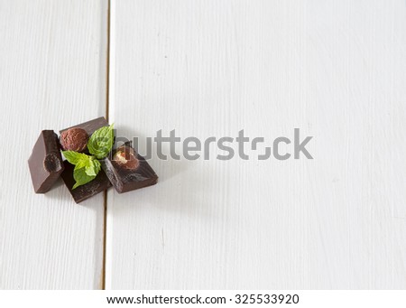 Dark chocolate with mint leaf with nuts on a wooden background white