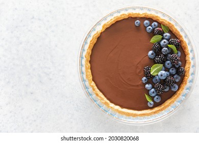 Dark chocolate mousse tart decorated with fresh blueberries and the mint, view from above, copy space for a text - Powered by Shutterstock