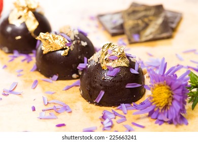 Dark Chocolate On A Wooden Table. Decorated With Gold Leaf. Selective Focus