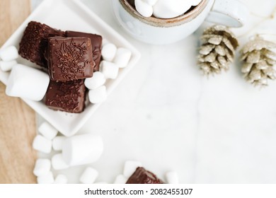 Dark Chocolate Petit Four Cake with Marshmallows and Hot Chocolate Flay Lay with Negative Space