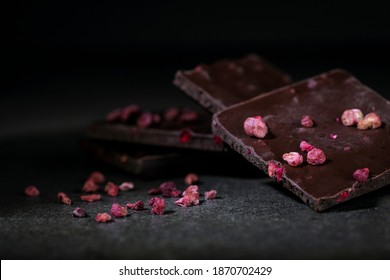 Dark chocolate stack with  raspberries, on  table. Natural light, selective focus.  Low key food. Dark food.