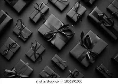 Dark Christmas theme. Square boxed gifts wrapped in black paper and ribbon arranged on black