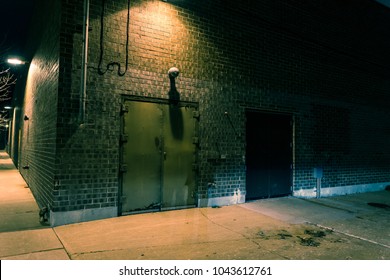 Dark City Street Corner And Alley With An Industrial Building Entrance At Night