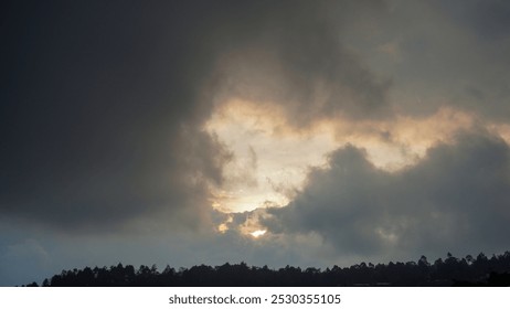 Dark clouds before rain, dark dramatic sky, extreme weather, the sun shines through the clouds.


