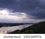 Dark clouds before a thunderstorm over a river paysage. the sun shines from below the clouds personifying a ray of hope and happy days after the storm