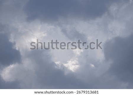 Dark clouds gather overhead with hints of bright sky visible as the weather changes in an afternoon sky