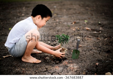 Dark Color tone, Young Thai boy planting little seedling on dry and crack empty land. Earthday concept.