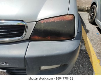 Dark Colored Plastic Car Headlight Torn And Damaged. Headlamp Tint Able To Prevent The Headlamp From Turning Into Yellowish, Protect The Headlamp From Stone Chips And Refine The Appearance Of The Car.