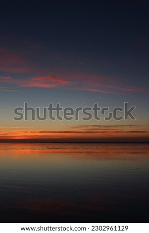 A dark colourful sky reflects in the calm water of the Wadden Sea