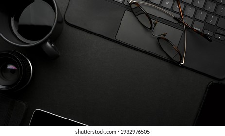 Dark creative flat lay workspace with eyeglasses, coffee cup, tablet keyboard and copy space, top view