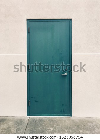 Dark cyan metal door on white concrete wall