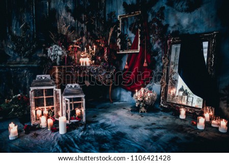 dark decor with dried flowers, vases, chandeliers, textured fabrics against the wall with a golden frame, a wooden table in a luxurious royal Victorian style, burning candles in old lanterns
