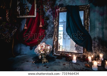 dark decor with dried flowers, vases, chandeliers, textured fabrics against the wall with a golden frame, a wooden table in a luxurious royal Victorian style,burning candles in old lanterns,old mirror