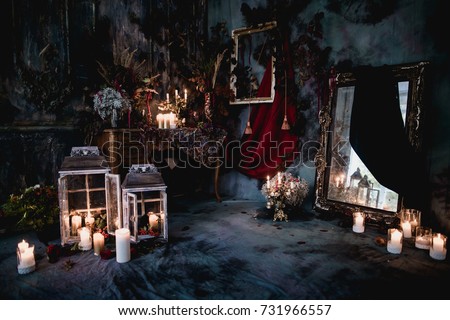 dark decor with dried flowers, vases, chandeliers, textured fabrics against the wall with a golden frame, a wooden table in a luxurious royal Victorian style, burning candles in old lanterns