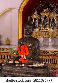 Dark deity statue draped with a red cloth in a Thai temple