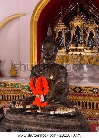 Dark deity statue draped with a red cloth in a Thai temple