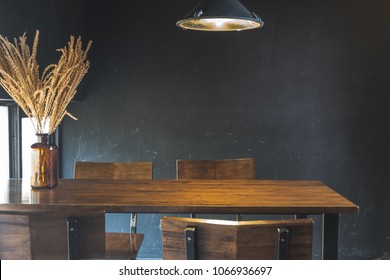 Dark dining table with wooden chair and dry flower in vintage design room