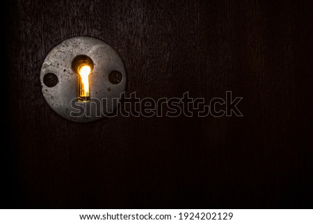 Dark door with keyhole with yellow light coming through