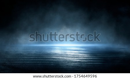 Dark dramatic abstract scene background. Neon glow reflected on the pavement. Smoke, smog and fog. Dark street, wet asphalt, reflections of rays in the water. Abstract dark blue background. 